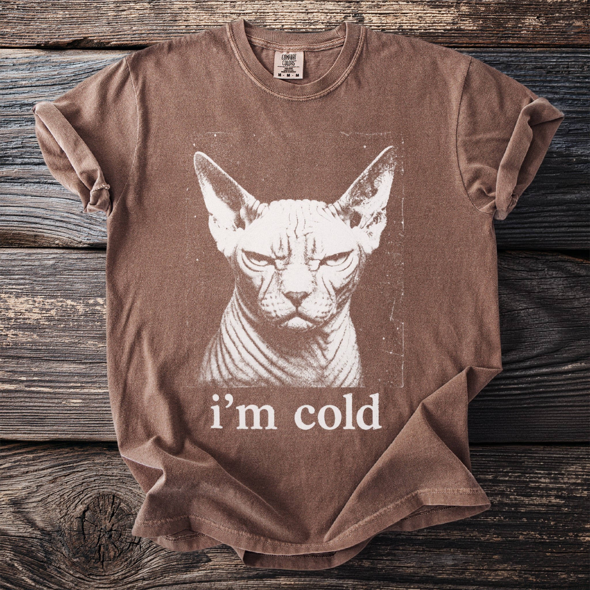 Brown t-shirt with a distressed print of a Sphynx cat's face and the text "i'm cold".