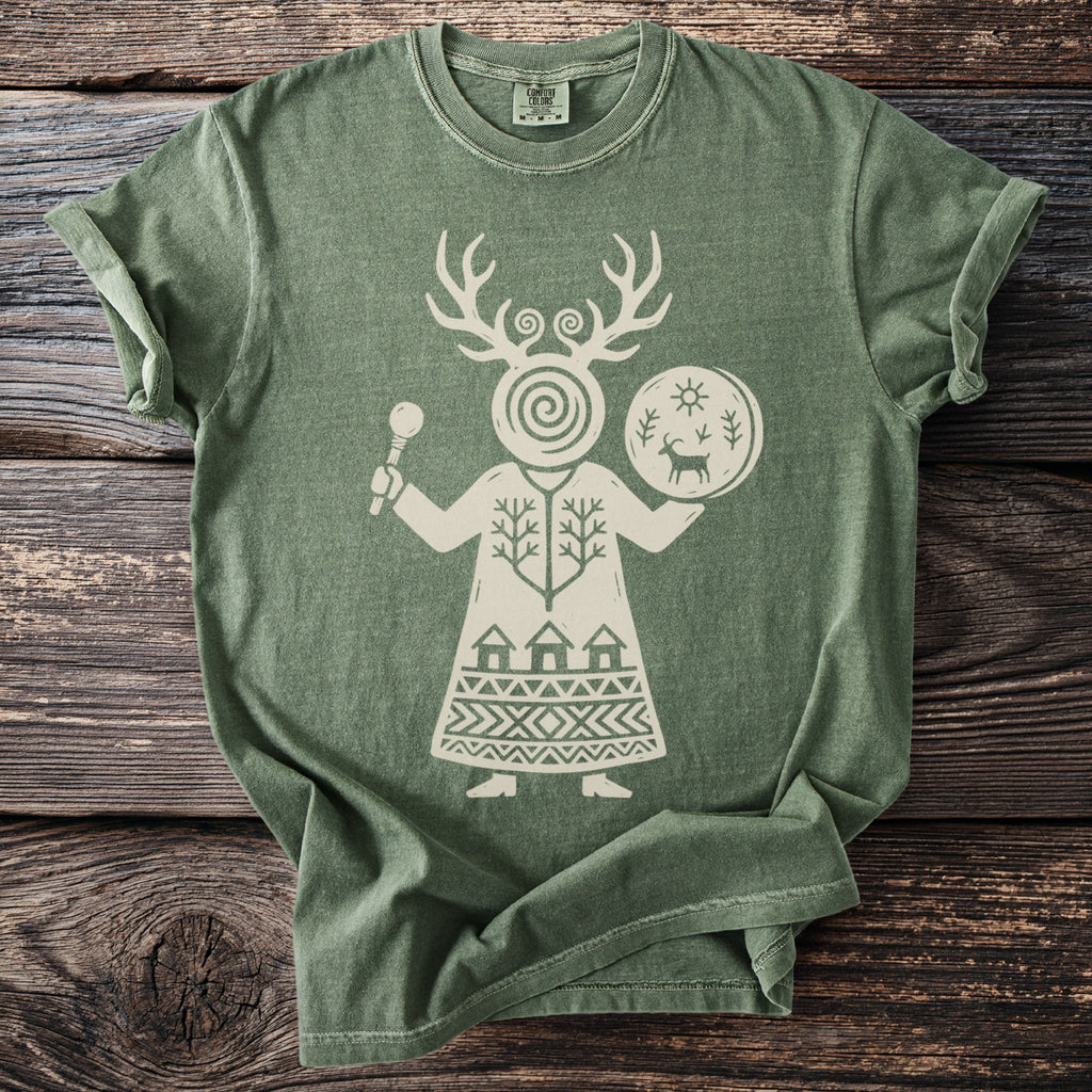 Green t-shirt with a white graphic of a figure with antlers, holding a drum and a staff.