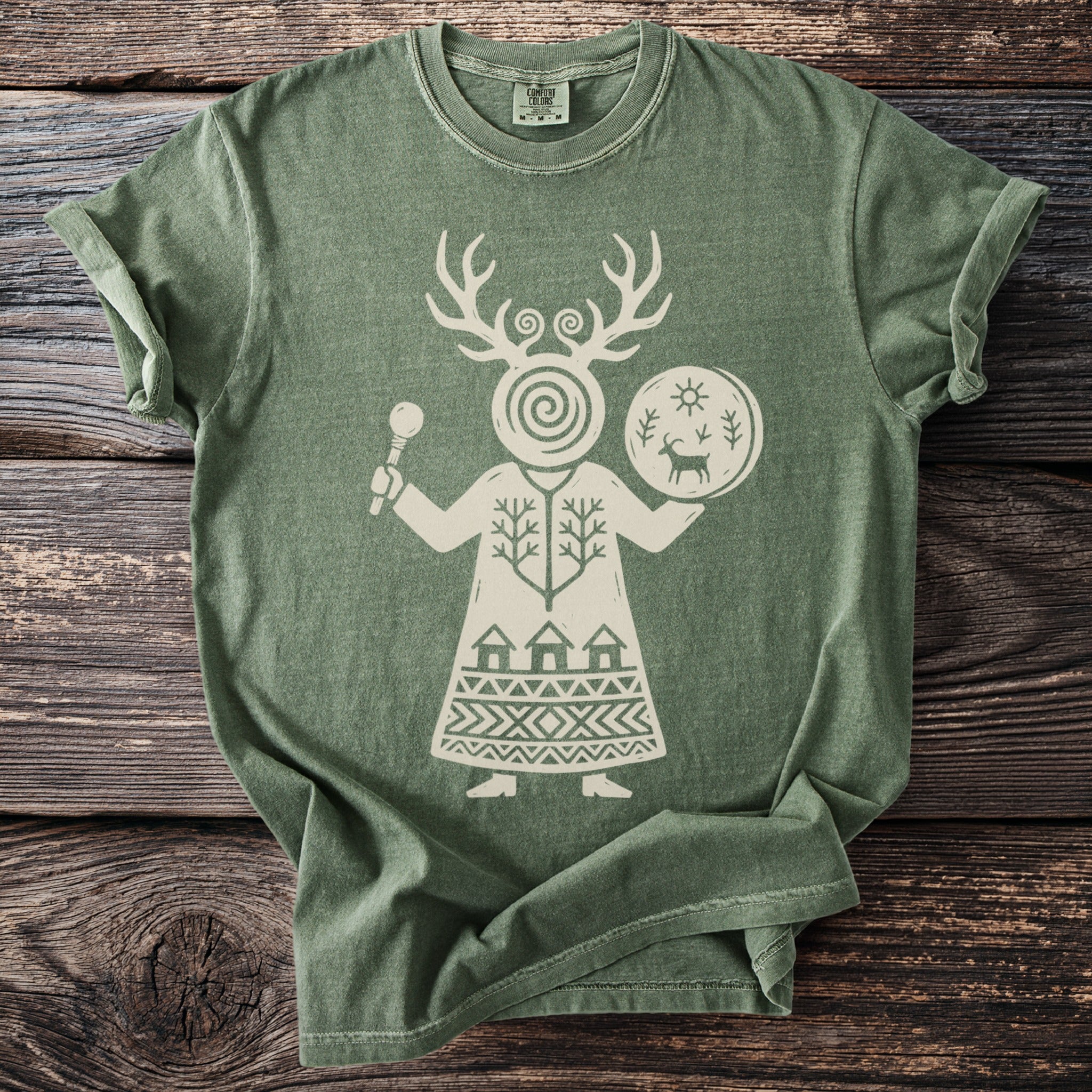 Green t-shirt with a white graphic of a figure with antlers, holding a drum and a staff.