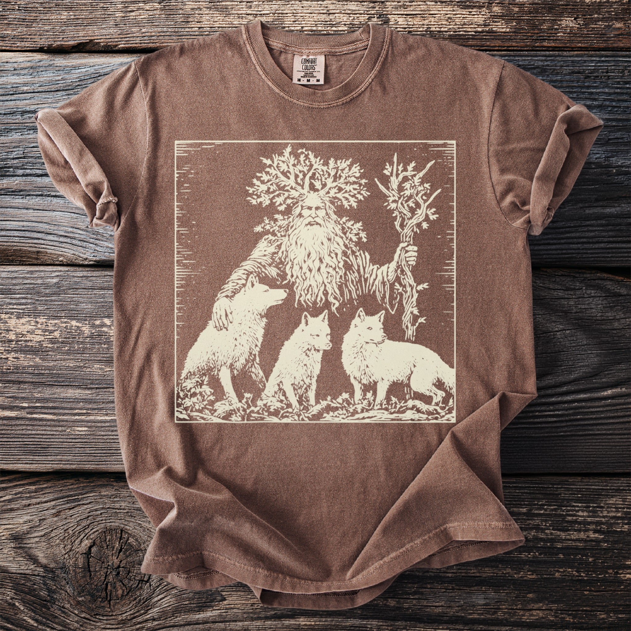 Brown t-shirt with a cream-colored graphic of a mythical forest man and three foxes.
