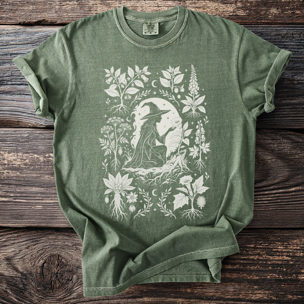Green t-shirt with a white graphic of a witch surrounded by plants and roots.