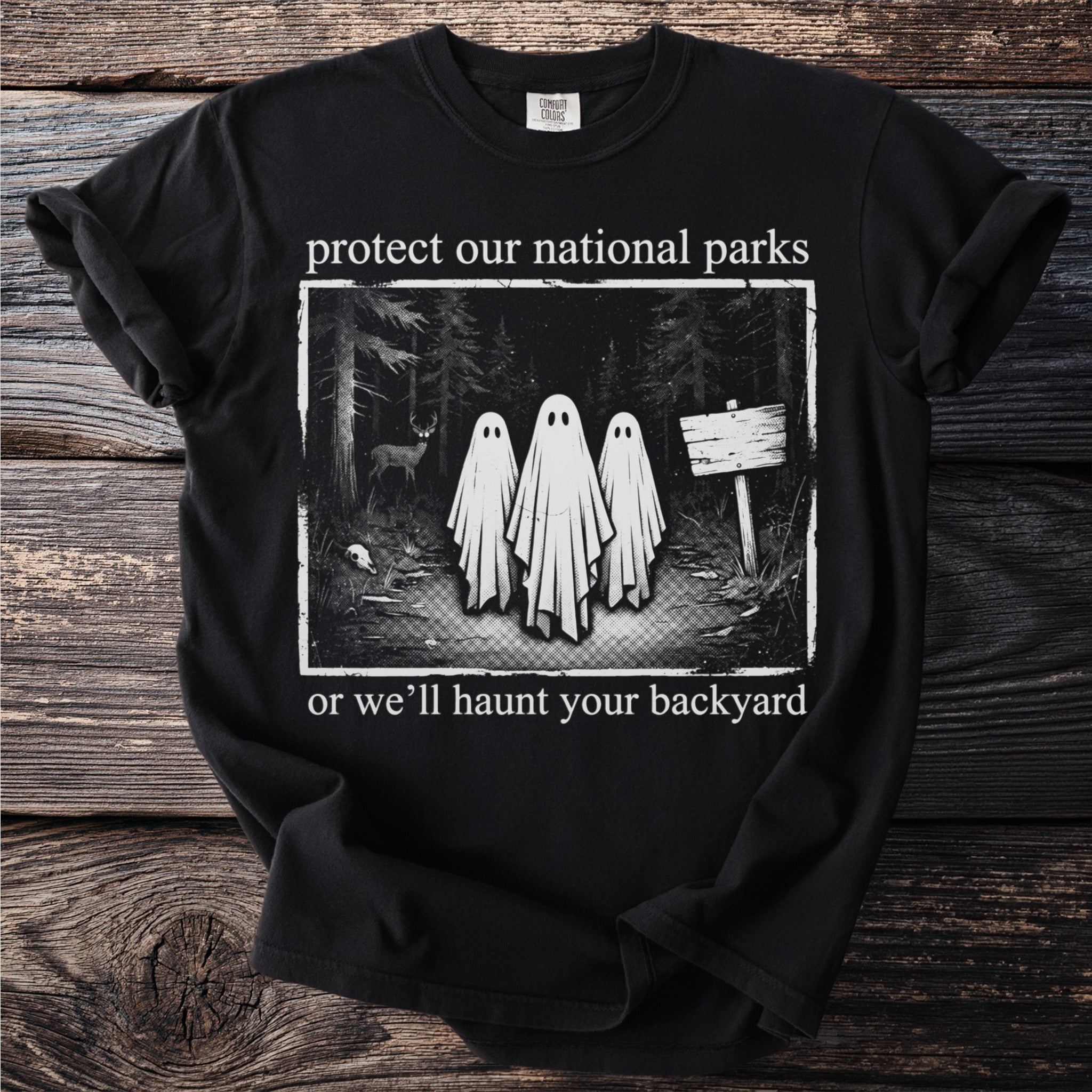 Black t-shirt with ghosts in a forest and text "protect our national parks or we'll haunt your backyard".