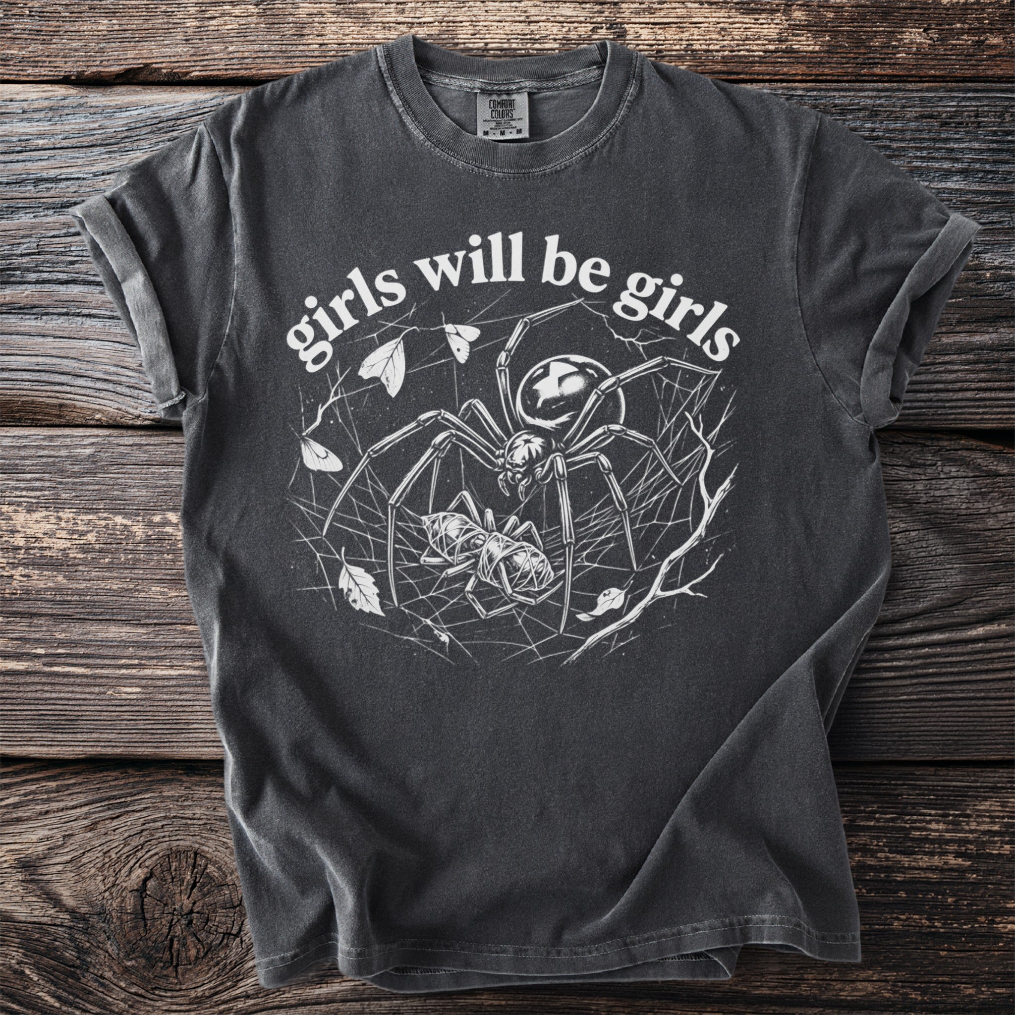 T-shirt with spiderwebs, a spider, a cocoon, and the text "girls will be girls".