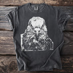 Dark t-shirt with a white close-up graphic of a pigeon's face staring straight ahead, on a wooden background.