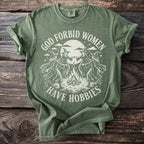Green t-shirt with white graphic of witches dancing around a campfire under a moon.