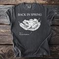 Dark grey t-shirt with "BACK IN SPRING" and a frog on leaves illustration.