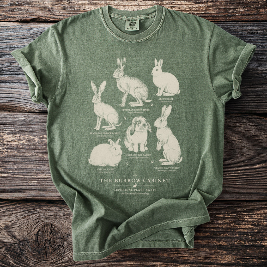 Green t-shirt with illustrations of six different rabbits and text "The Burrow Cabinet".