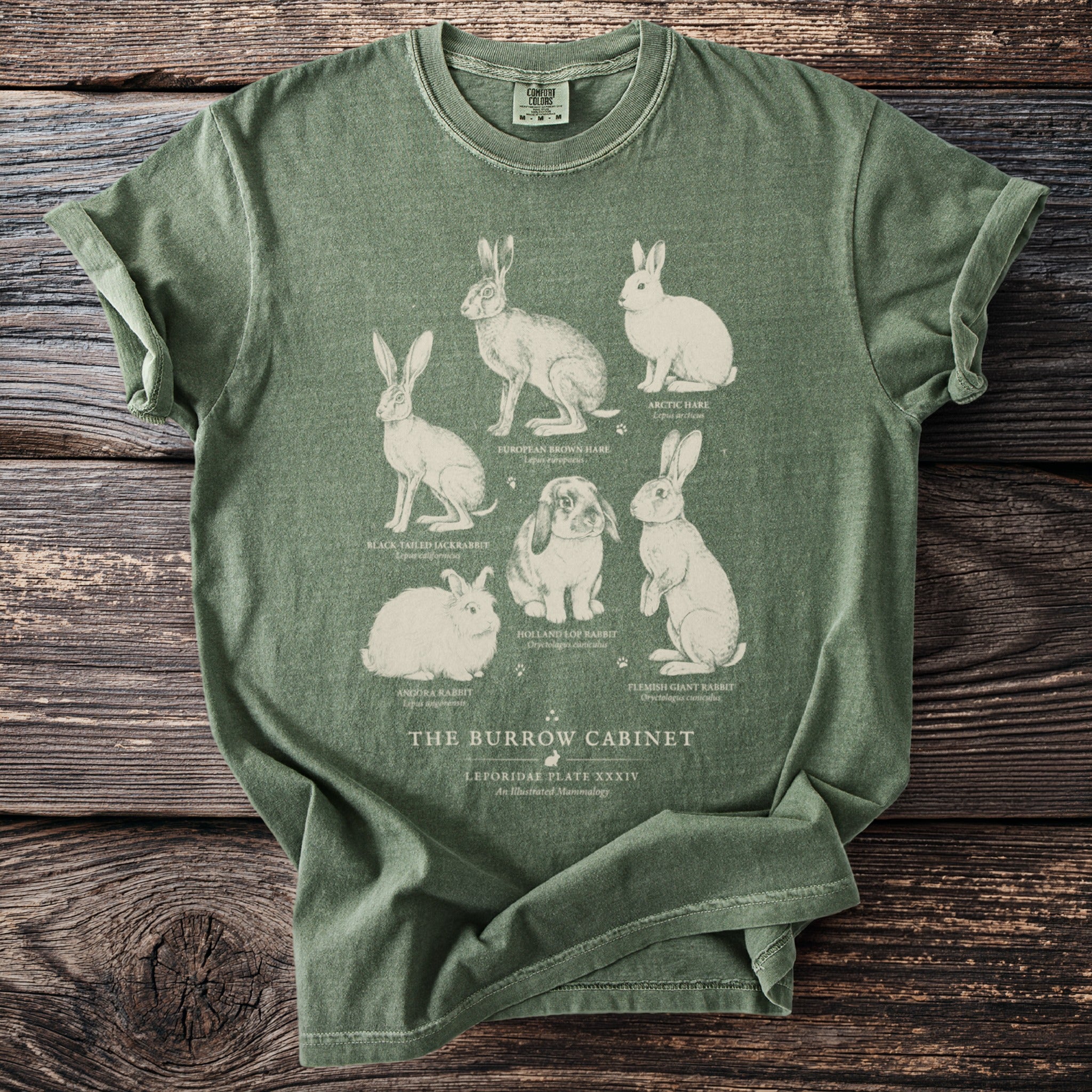 Green t-shirt with illustrations of six different rabbits and text "The Burrow Cabinet".