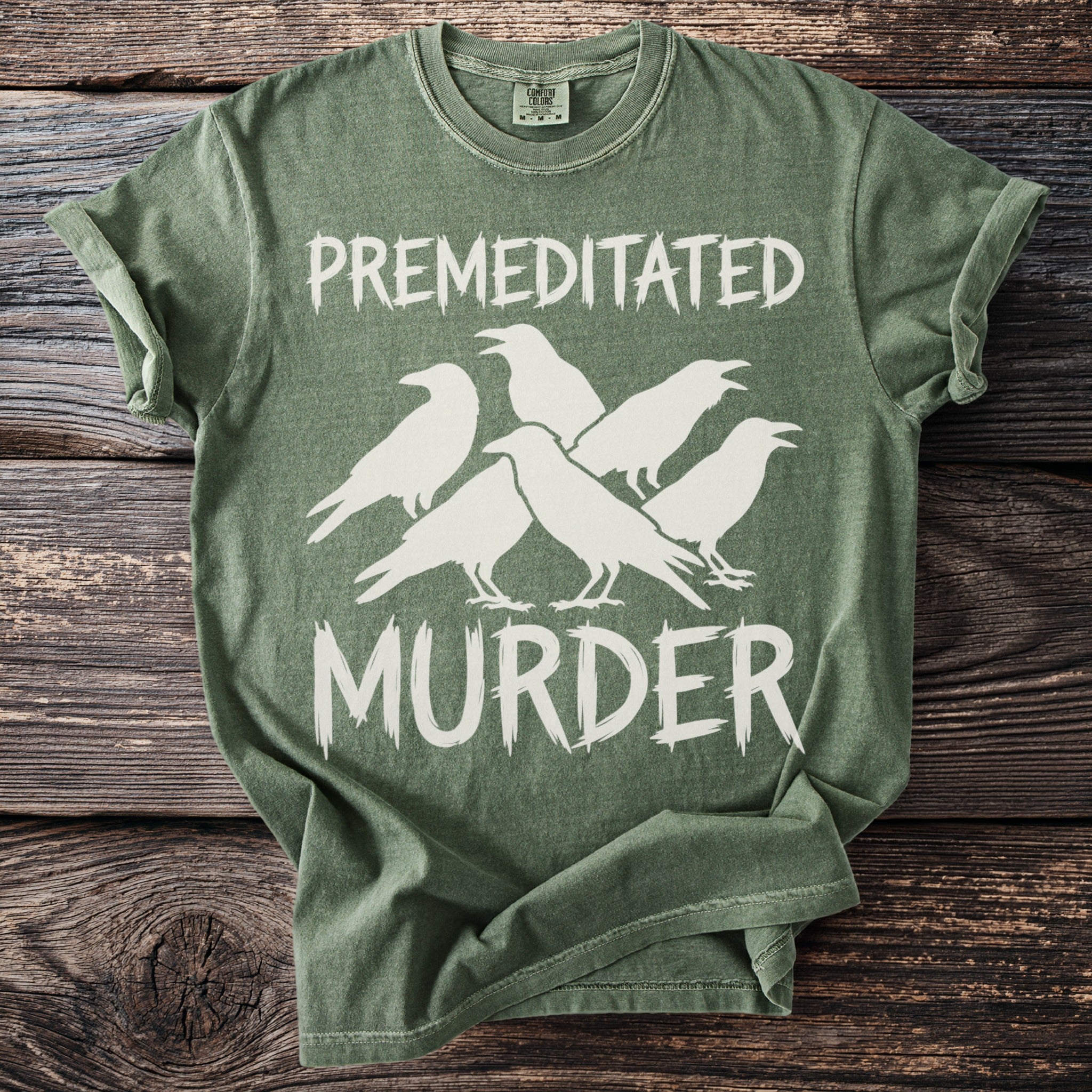 Green t-shirt with white text "PREMEDITATED MURDER" and silhouette of five crows.