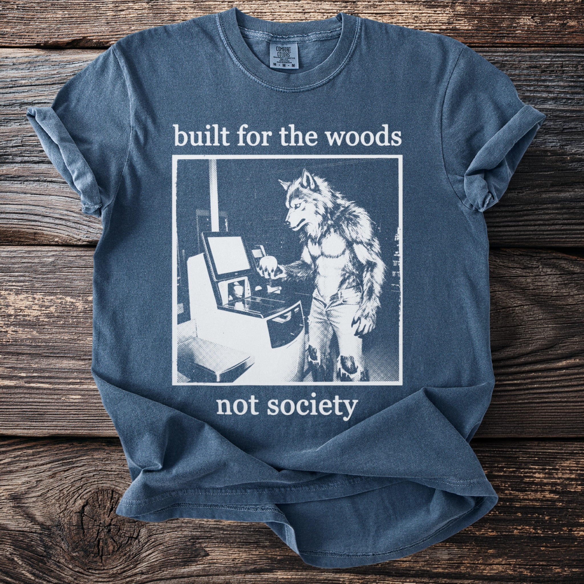 Blue t-shirt with white text and graphic of a werewolf at a machine.