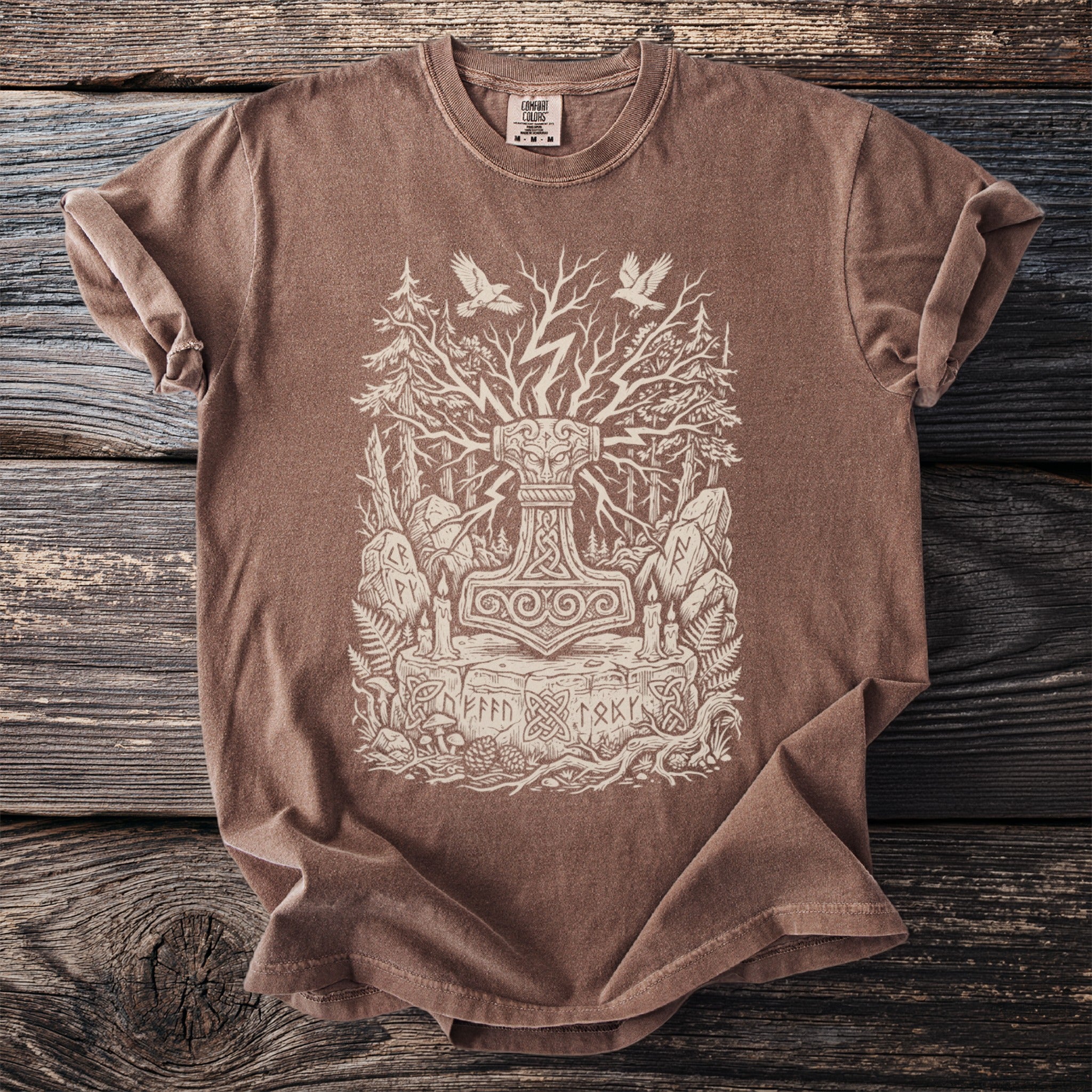 Brown t-shirt with a cream linocut style print of Thor's hammer, Yggdrasil, and Norse runes.