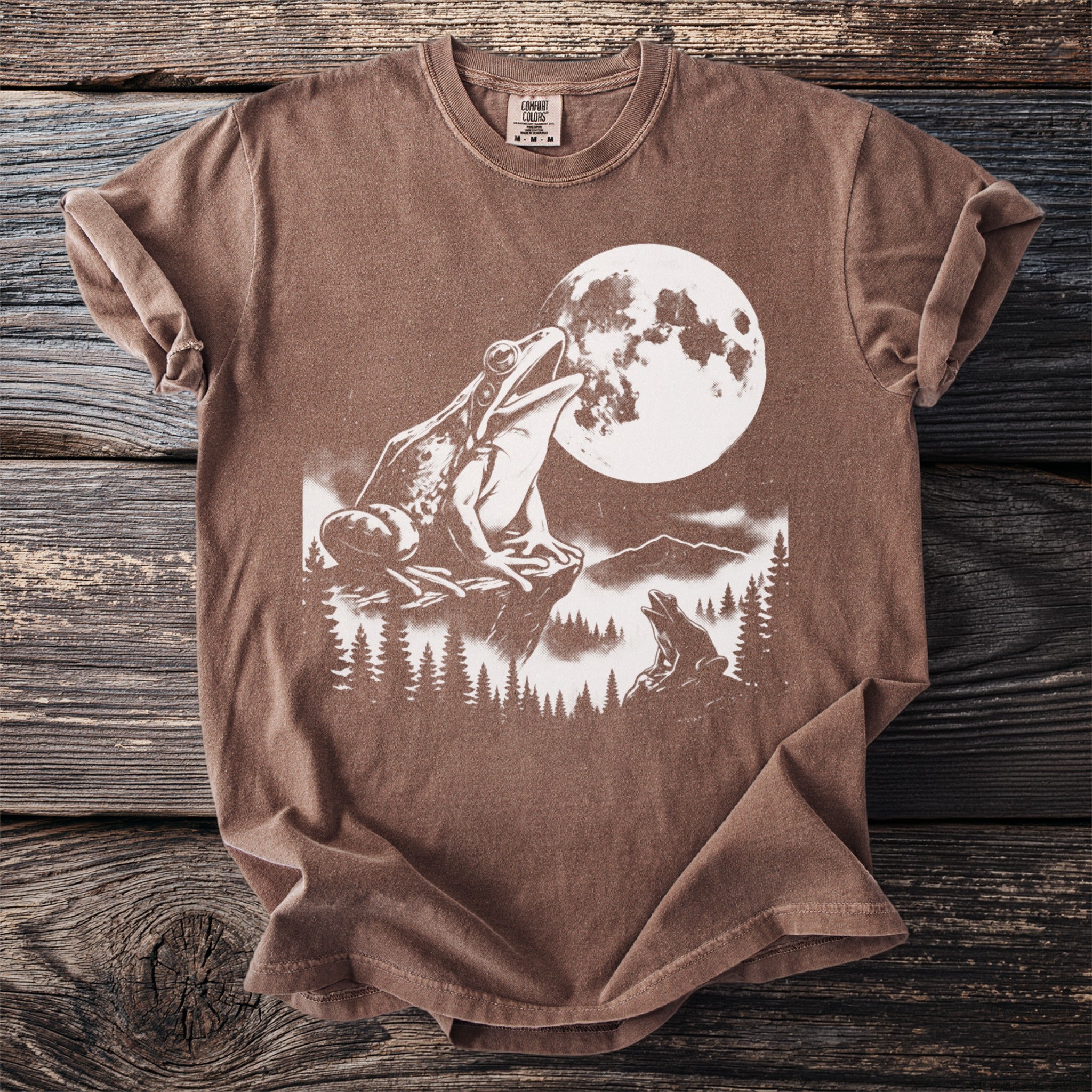Brown t-shirt with a white graphic of two frogs and a full moon.