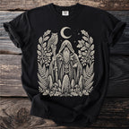 Black t-shirt with a cream linocut print of a wizard holding an owl staff and surrounded by nature.