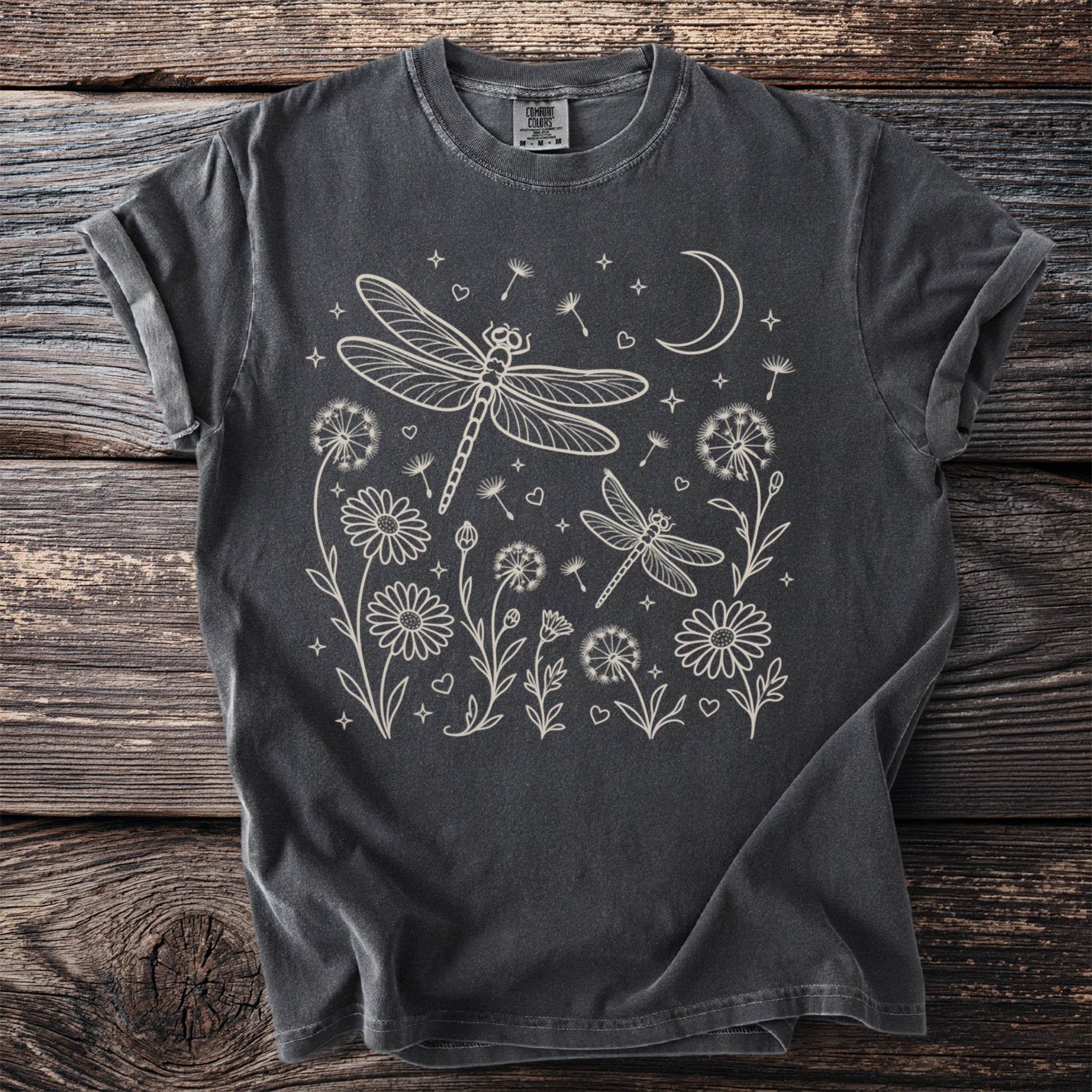 Dark grey t-shirt with cream line art of dragonflies, flowers, a moon, and stars.