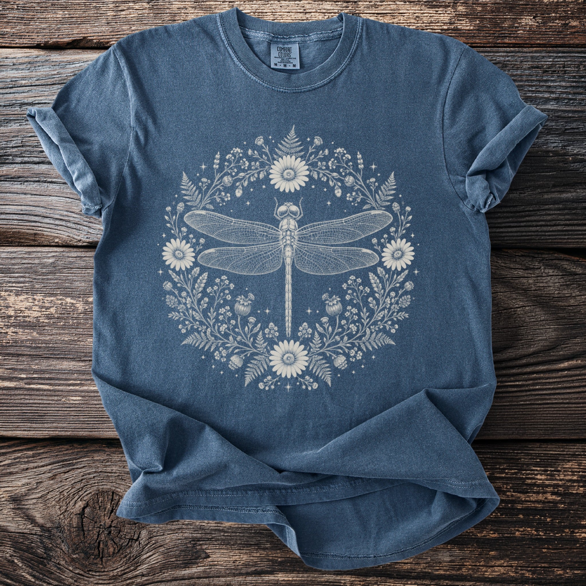 Blue t-shirt with a white dragonfly and floral wreath graphic.