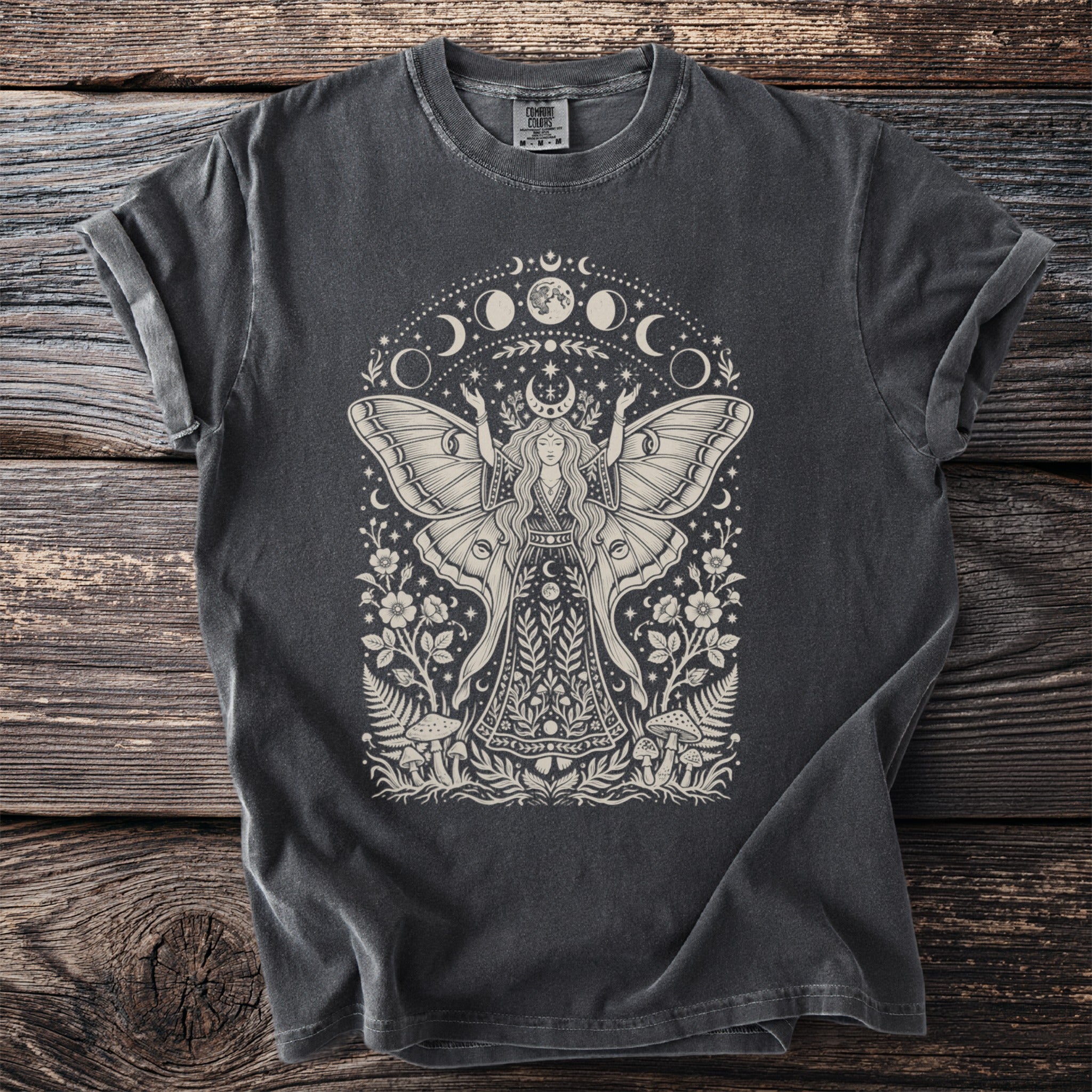 Dark grey t-shirt with a cream graphic of a moth-winged woman, moons, stars, and foliage.