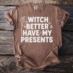 Brown t-shirt with white text "Witch Better Have My Presents" and decorative elements.