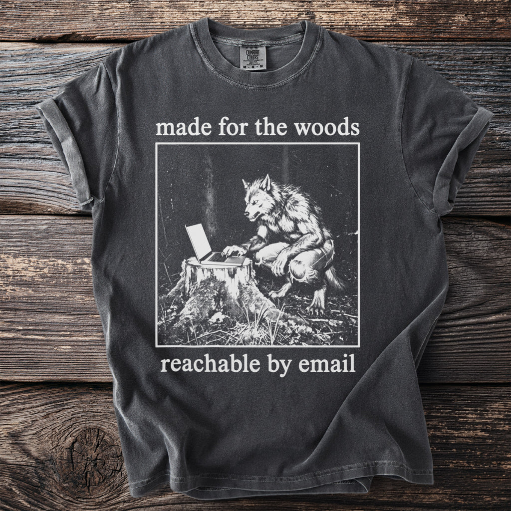 Dark grey t-shirt with a graphic of a werewolf using a laptop on a tree stump, text "made for the woods reachable by email".