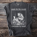 Dark grey t-shirt with a graphic of a werewolf using a laptop on a tree stump, text "made for the woods reachable by email".