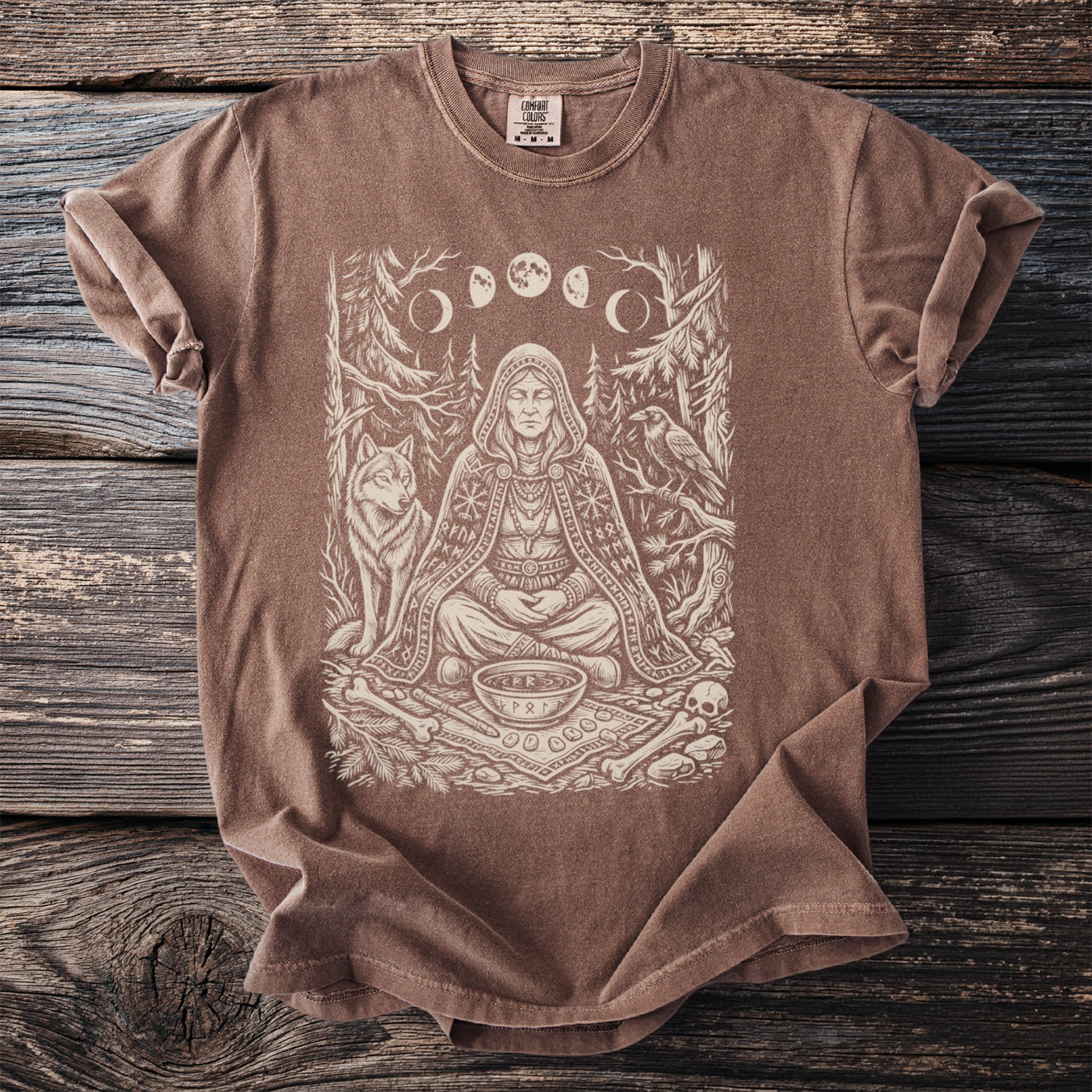 Brown t-shirt with a line art print of a robed figure, wolf, raven, and moon phases.