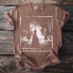 Brown t-shirt with a white graphic of three witches around a bonfire, text reads "girls will be girls".