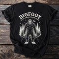 Black t-shirt with Bigfoot graphic and "Pacific Northwest Cryptid Legend" text.