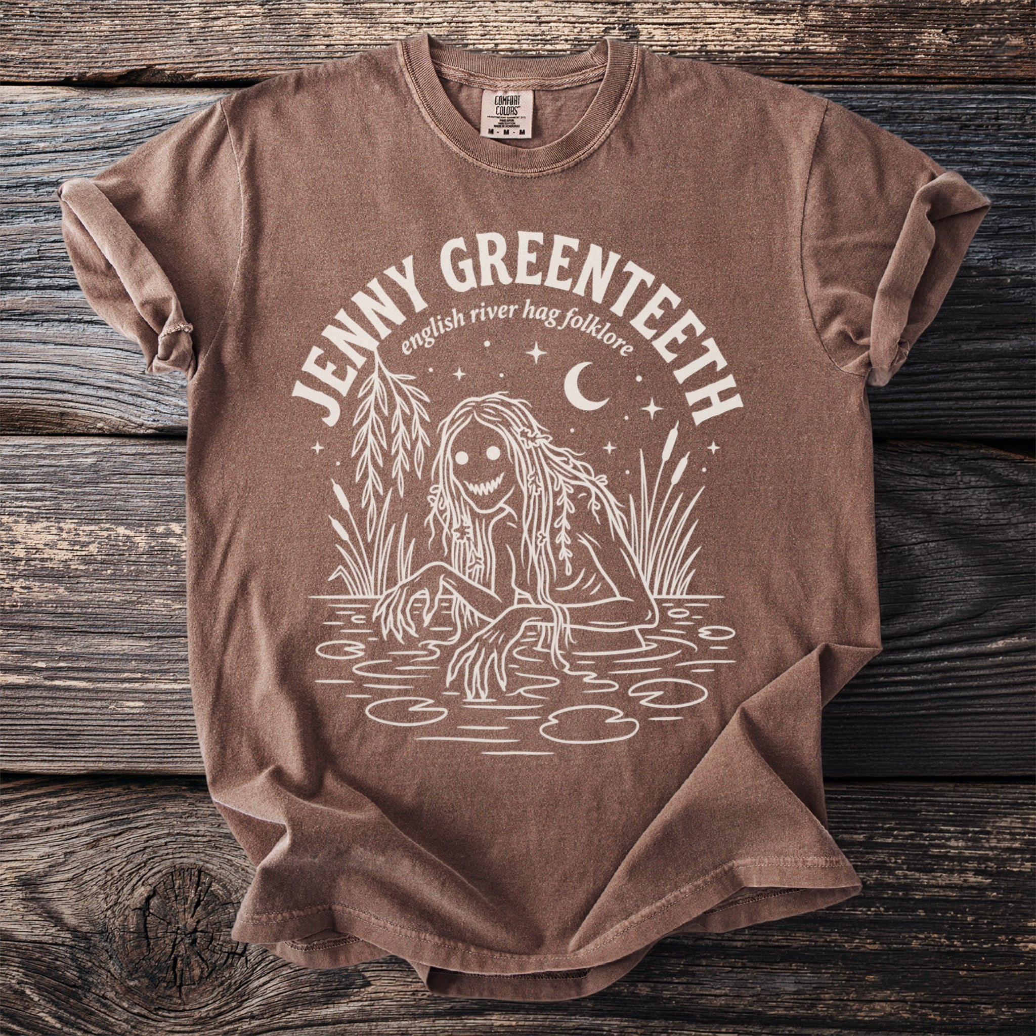 Brown t-shirt with white graphic of a swamp creature and text "JENNY GREENTEETH english river hag folklore".