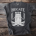 Dark gray t-shirt with "HECATE" in white text above a design of three women.