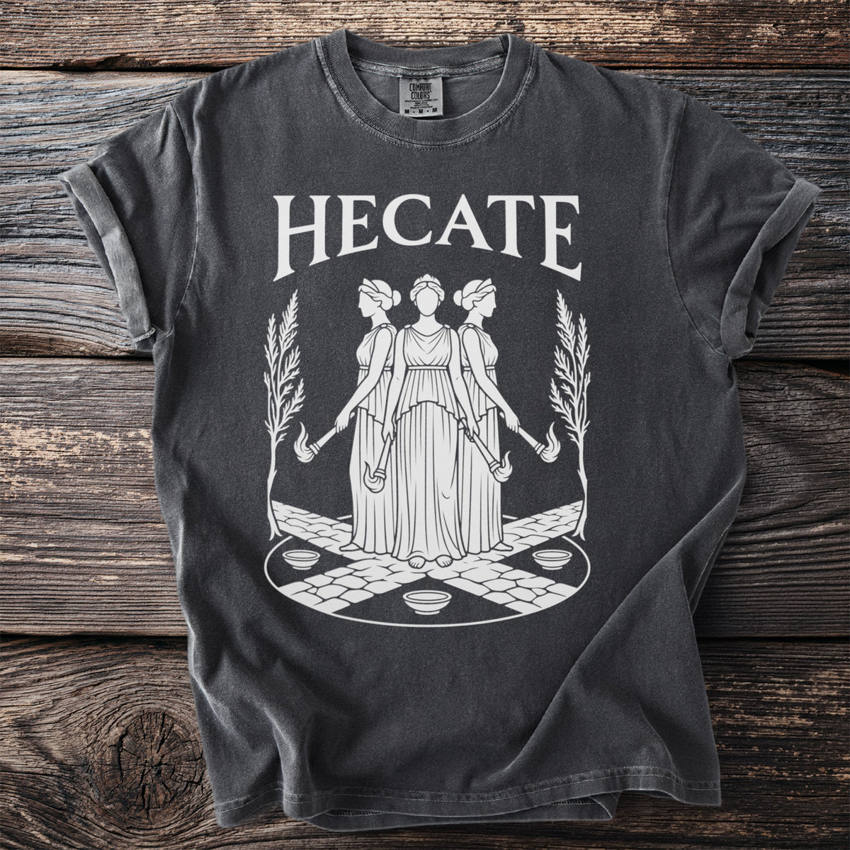Dark gray t-shirt with "HECATE" in white text above a design of three women.