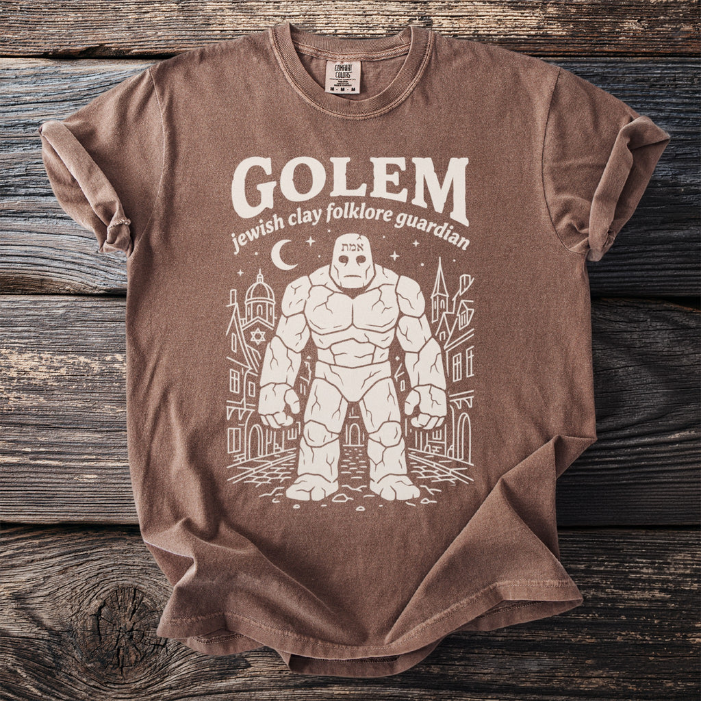 Brown t-shirt with white graphic of a Golem, moon, and city buildings