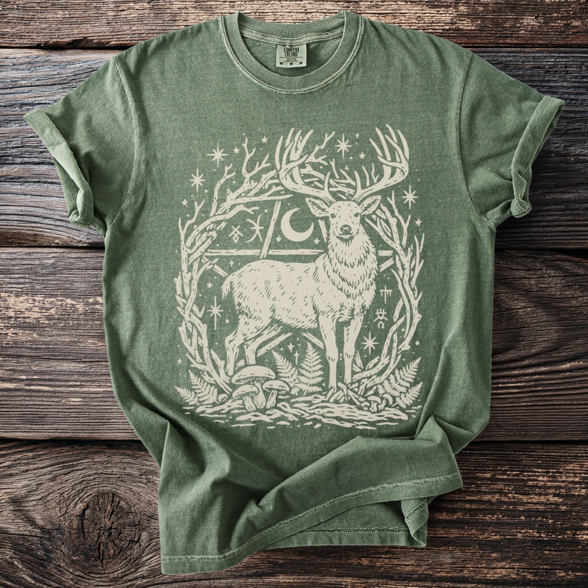 Green t-shirt with a white stag, moon, stars, and woodland elements print.