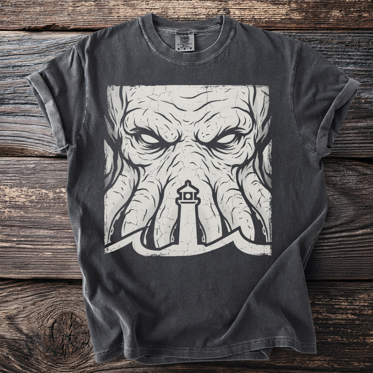 Dark t-shirt with a distressed graphic of a kraken-like face and lighthouse.