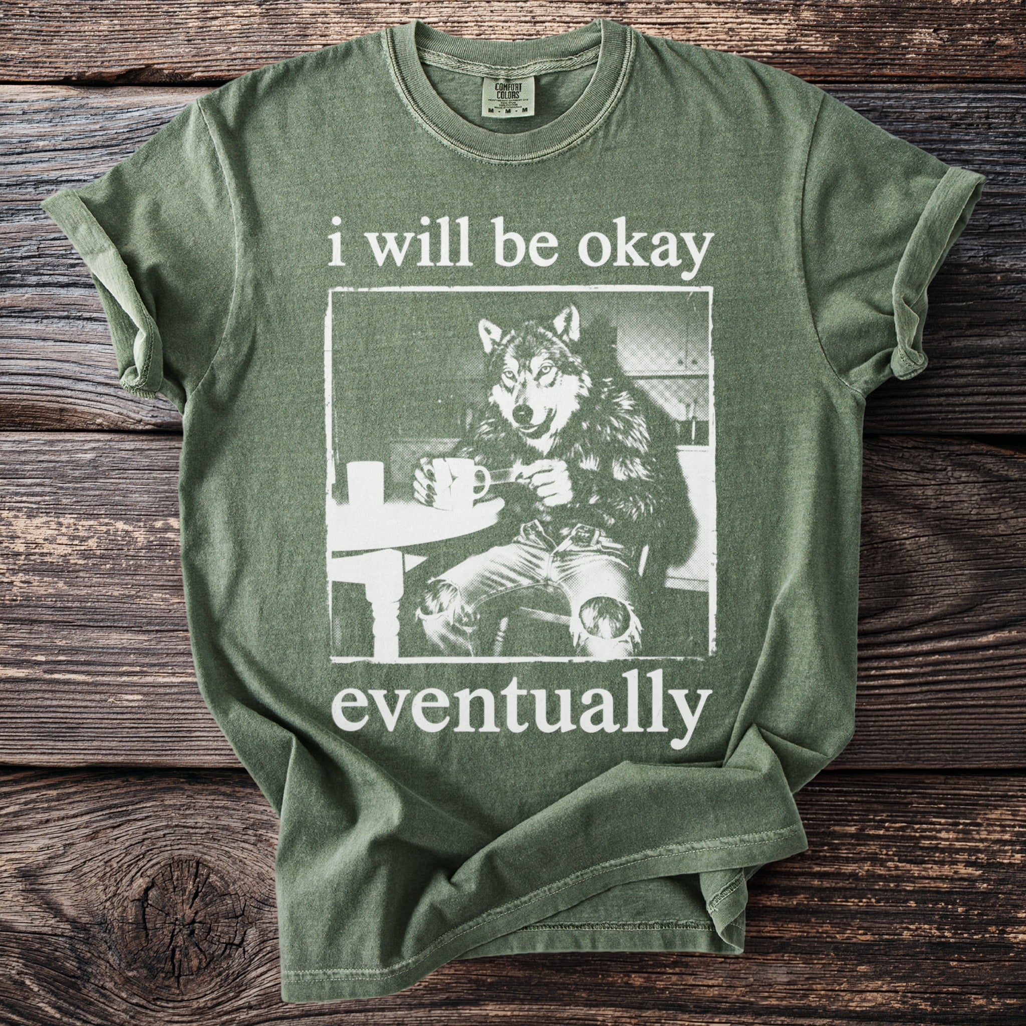 Green t-shirt with text "i will be okay eventually" and wolf graphic.