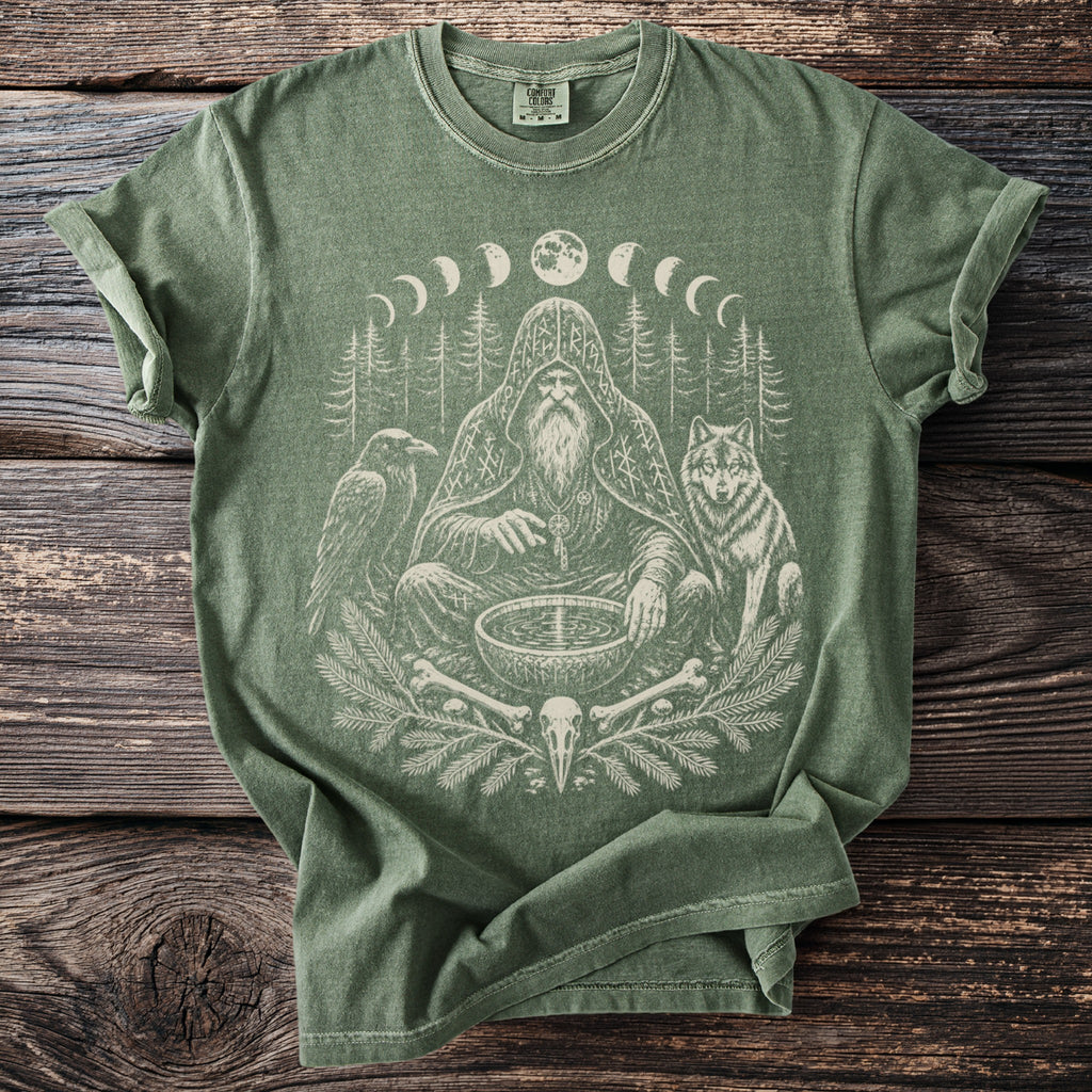 Green t-shirt with occult forest graphic featuring a man, raven, wolf, moon phases, and skull.