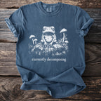 Blue t-shirt with a distressed graphic of a frog and mushrooms, text reads "currently decomposing".