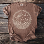 Brown t-shirt with a circular white graphic of a dragonfly, moon, and wildflowers.