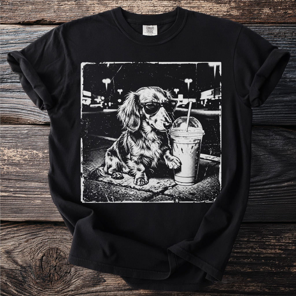 Black t-shirt with vintage style graphic of a dachshund wearing sunglasses with iced coffee.