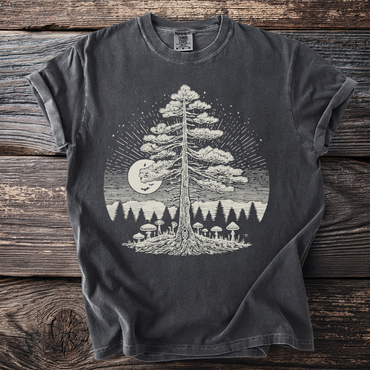 Dark gray t-shirt with a white graphic of a pine tree, mushrooms, moon, and stars.