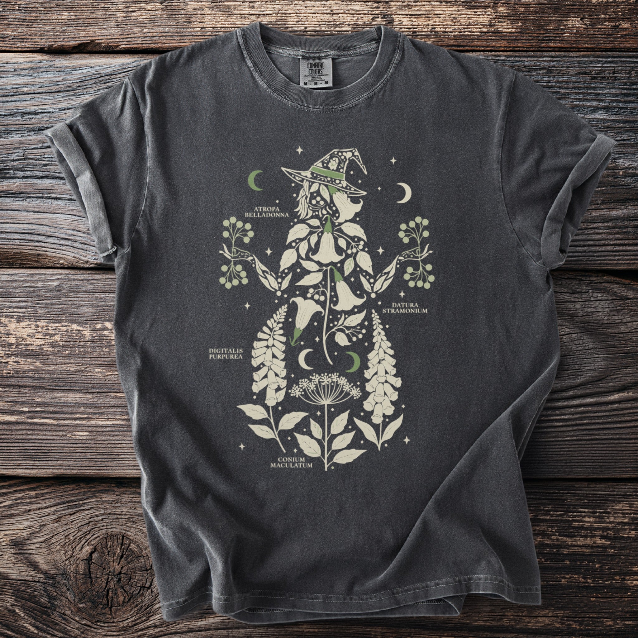 Dark gray t-shirt with botanical illustration of a witch silhouette and plant names.