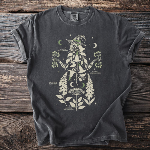 Dark gray t-shirt with botanical illustration of a witch silhouette and plant names.