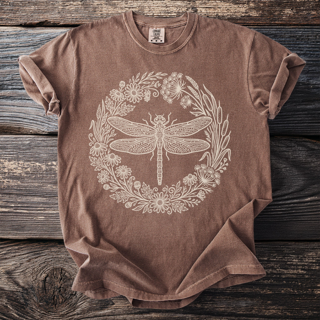 Brown t-shirt with a white dragonfly and floral wreath graphic and "Comfort Colors" label.