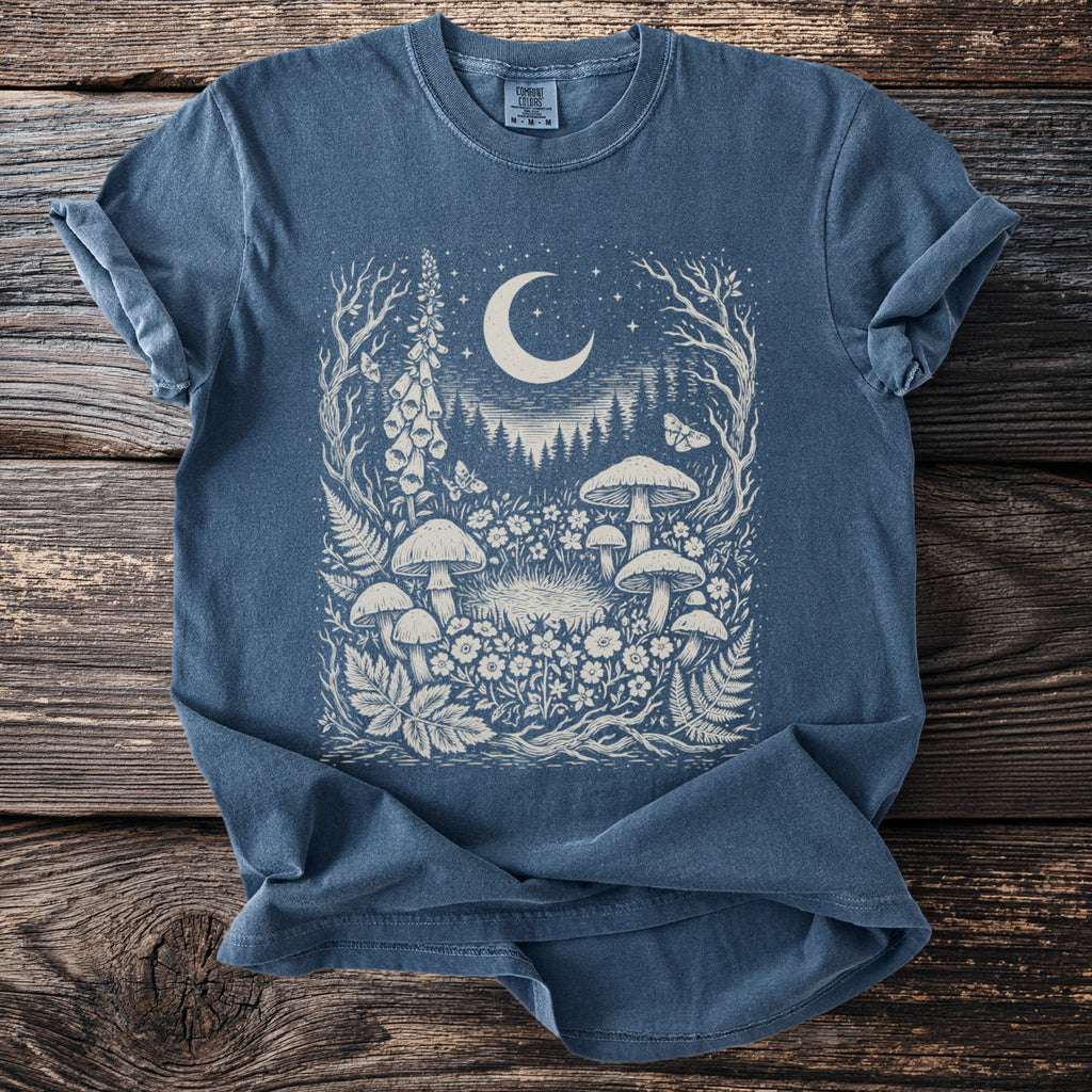 Blue comfort colors t-shirt with white moon, mushrooms, flowers, and moths graphic.