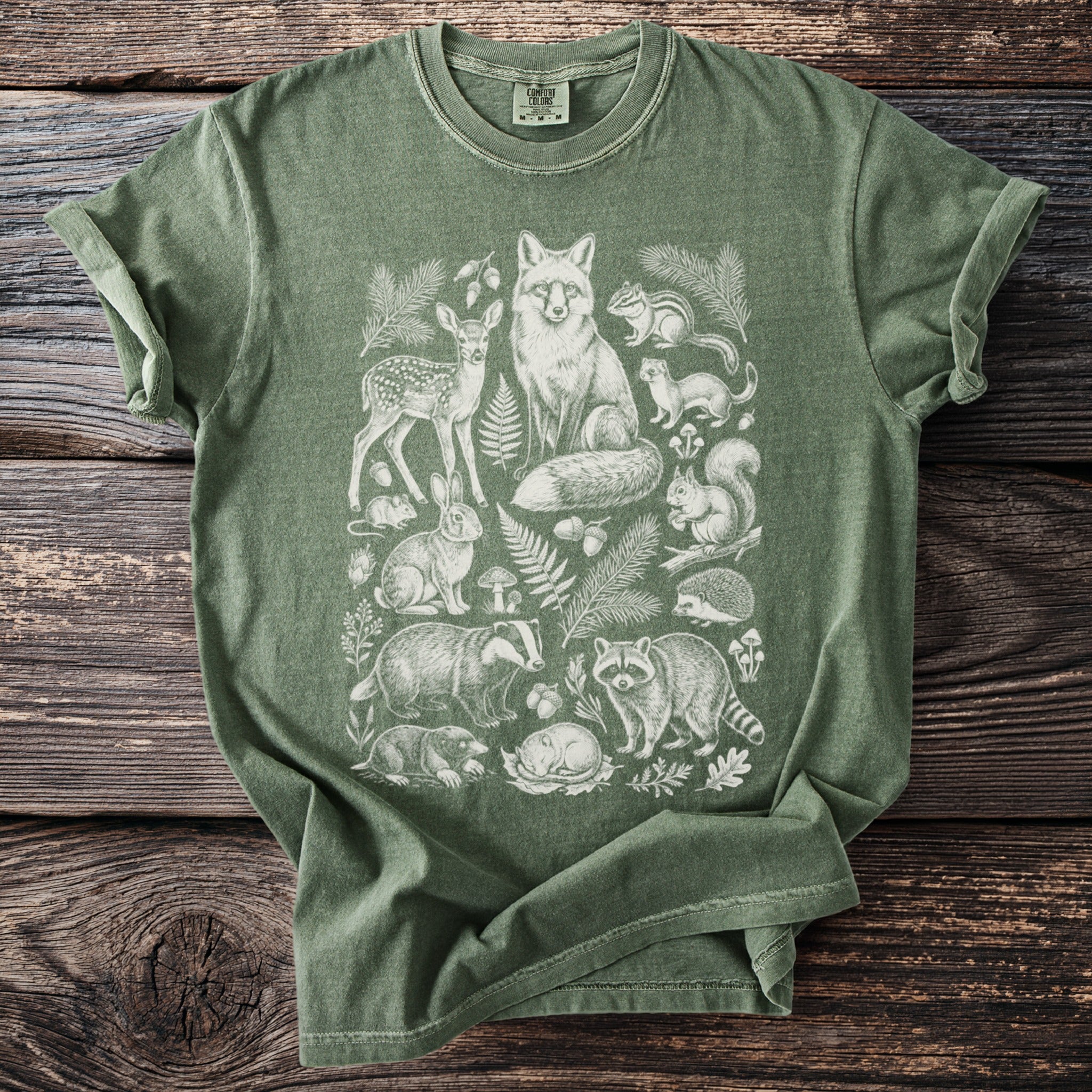 Green Comfort Colors t-shirt with detailed white illustration of woodland animals and foliage.