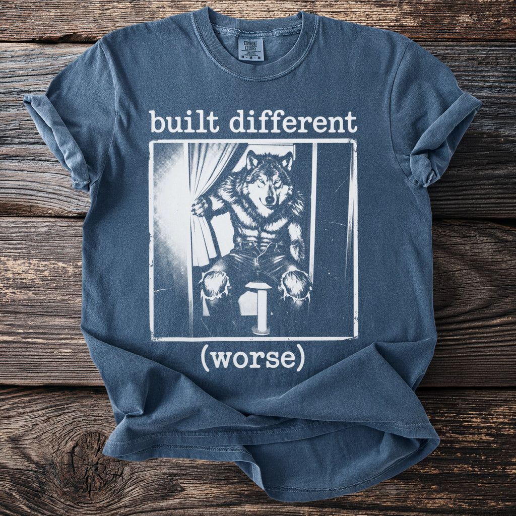 Blue t-shirt with text "built different (worse)" and graphic of a wolf on a stool.