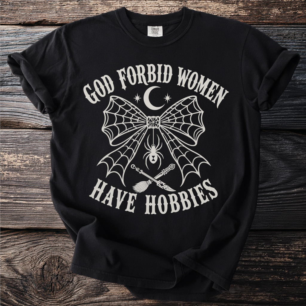 Black t-shirt with "God Forbid Women Have Hobbies" text and witchy graphics.