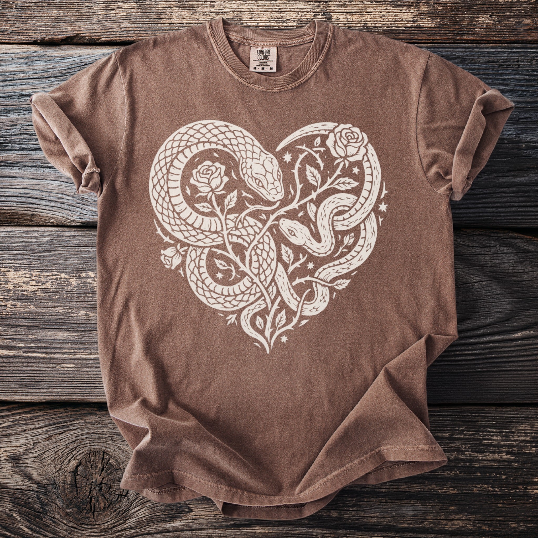 Brown t-shirt with white heart design of intertwined snakes and roses.