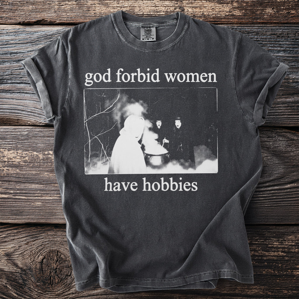 Dark t-shirt with "god forbid women have hobbies" text and a vintage image.