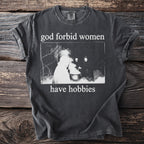 Dark t-shirt with "god forbid women have hobbies" text and a vintage image.