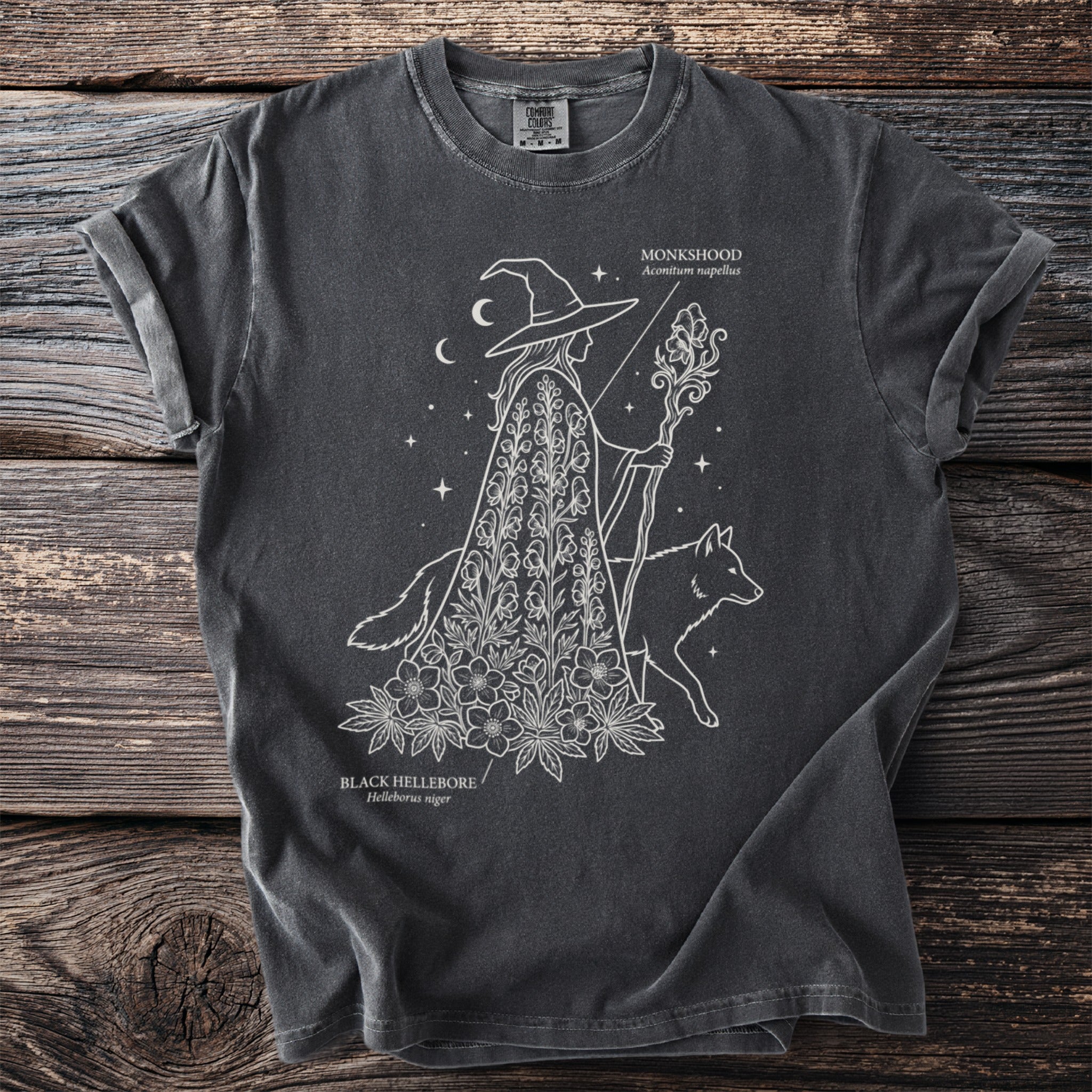 Dark gray t-shirt with white line art of a witch, wolf, monkshood, and black hellebore.