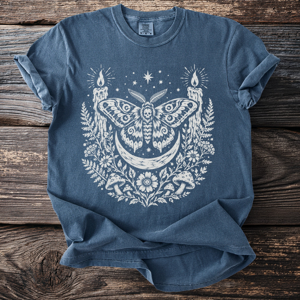 Blue t-shirt with white moth, crescent moon, candles, and floral graphic.